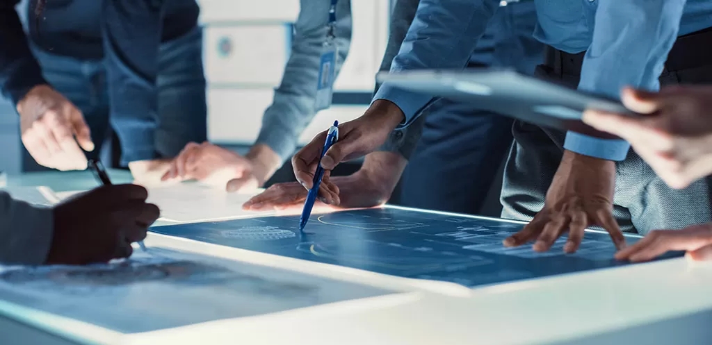 Engineer, Scientists and Developers Gathered Around Illuminated Conference Table in Technology Research Center, Talking, Finding Solution and Analysing Design. Close-up Hands Shot